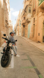 Man riding motorcycle on street amidst buildings in city