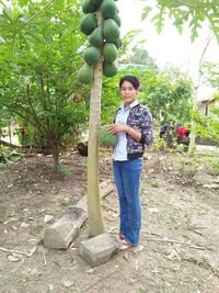 Portrait of smiling young woman standing against tree