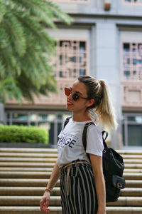 Pretty young white tourist girl walking down stairs as she walks through the streets of singapore