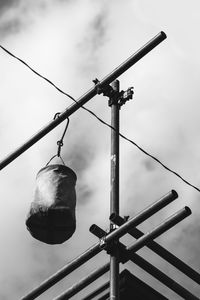 Low angle view of punching bag hanging on pole against sky