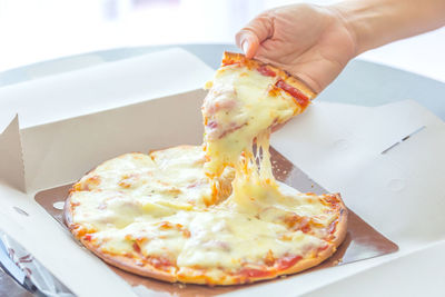 Close-up of hand holding pizza in plate