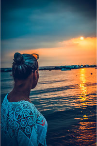 Midsection of woman against sea during sunset
