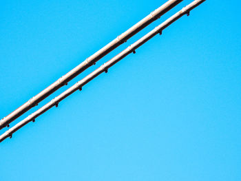 Low angle view of telephone pole against clear blue sky