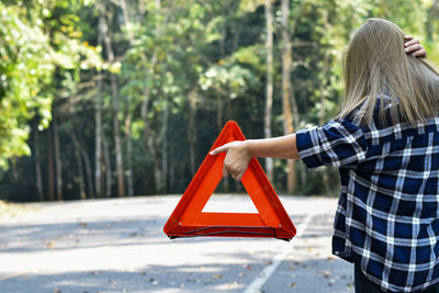 Rear view of woman with red umbrella standing against trees