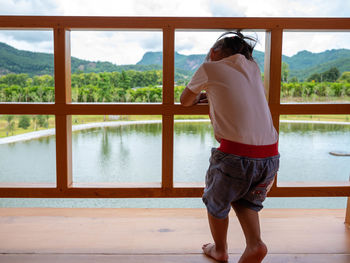 Rear view of man standing by swimming pool