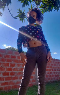 Low angle view of man standing against brick wall