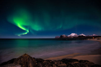 Scenic view of sea and mountains against sky at night