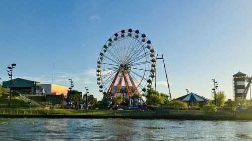 Ferris wheel by buildings against clear sky