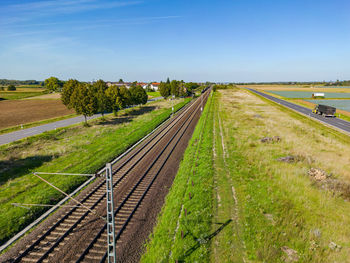 A railroad line next to a road in the sunshine
