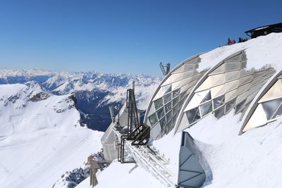 Panoramic view of snow covered mountains against blue sky