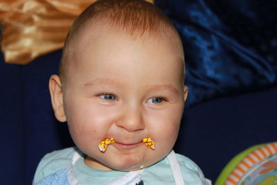 Smiling baby boy with paper in mouth at home