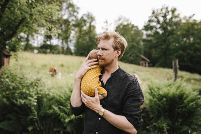 Man holding ice cream standing against plants