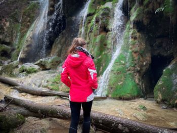 Rear view of young woman standing in front of a big waterfall