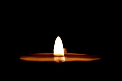 Close-up of lit candle against black background