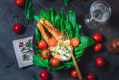 A plate with fresh green raw spinach and fried wild salmon, tomatoes and cream cheese sauce 