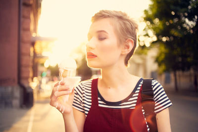 Portrait of young woman drinking drink in city