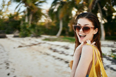 Portrait of young woman wearing sunglasses standing at beach