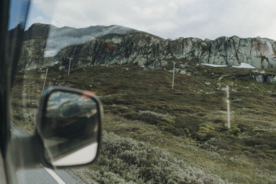 Scenic view of mountains seen through glass window against sky