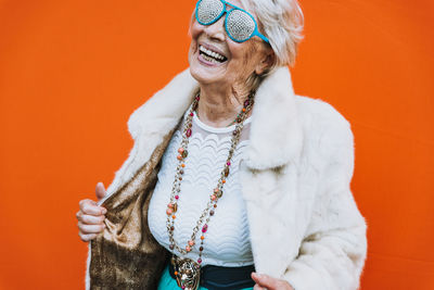 Portrait of smiling woman standing against red background