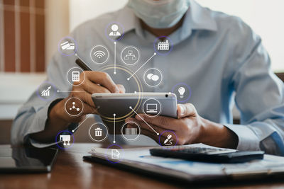 Midsection of man using mobile phone on table