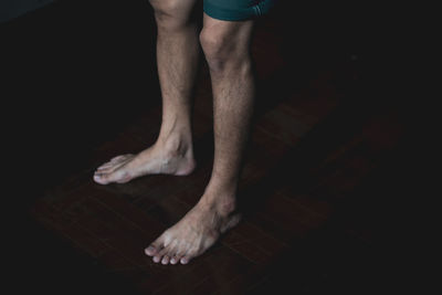 Low section of man standing over black background