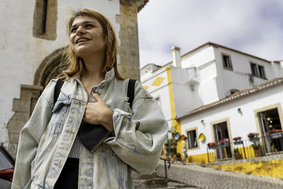 Low angle view of woman looking away against buildings in city