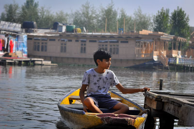 Boy sitting on boat in river