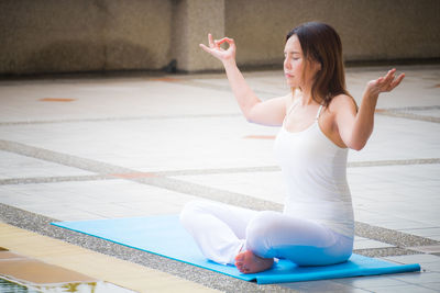 Young woman holding umbrella while sitting on floor