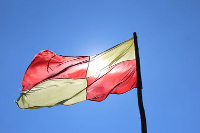 Low angle view of flag against clear blue sky