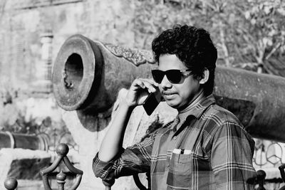 Portrait of young man holding sunglasses