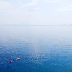 Scenic view of sea against sky with kayakers