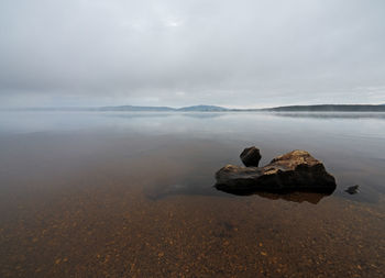 Rocks on sea shore against sky