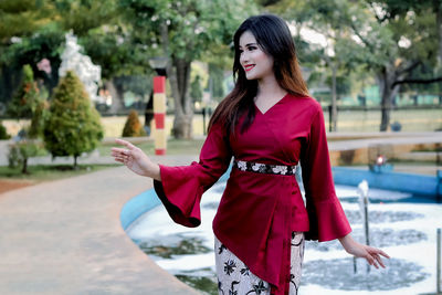 Young woman standing with red umbrella