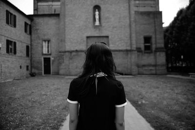 Rear view of woman standing against church