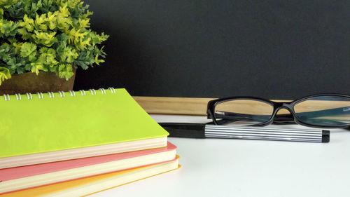 Close-up of spiral notebooks and eyeglasses on table