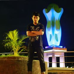 Portrait of young man standing against illuminated wall