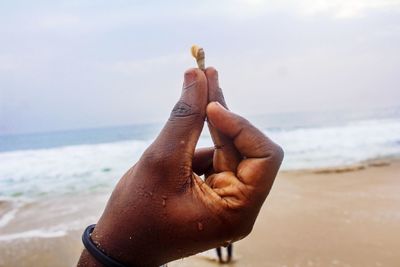 Close-up of hand on sea shore