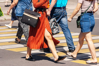 Low section of people walking on street in city