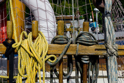 Close-up of ropes tied up to wooden railing