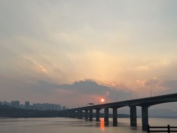 Bridge over river against sky during sunset