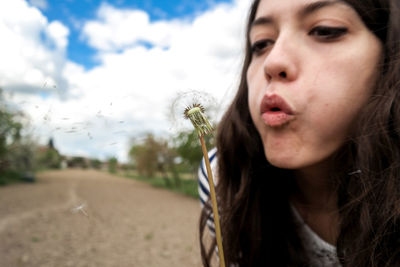 Close-up of woman blowing dandelion