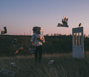 Paper flying over field against sky during sunset