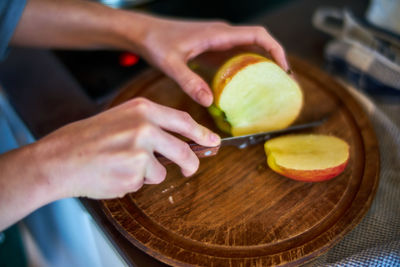 Cropped hands of woman cutting apple at home