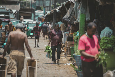 Rear view of people walking on street in city