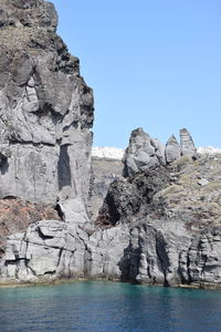 Rock formations by sea against clear blue sky