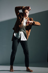 Full length of young man standing against wall