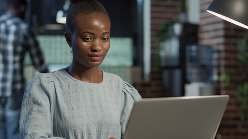 Portrait of young woman using laptop at office