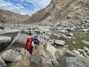 Rear view of people on rocks by mountain