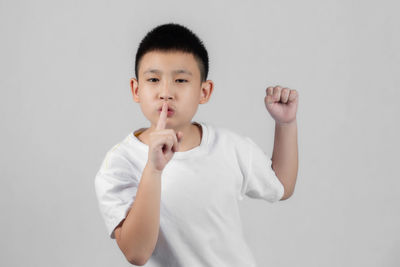 Portrait of cute boy standing against white background