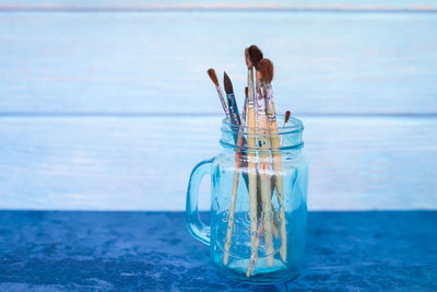 Reflection of woman in glass container on table at beach